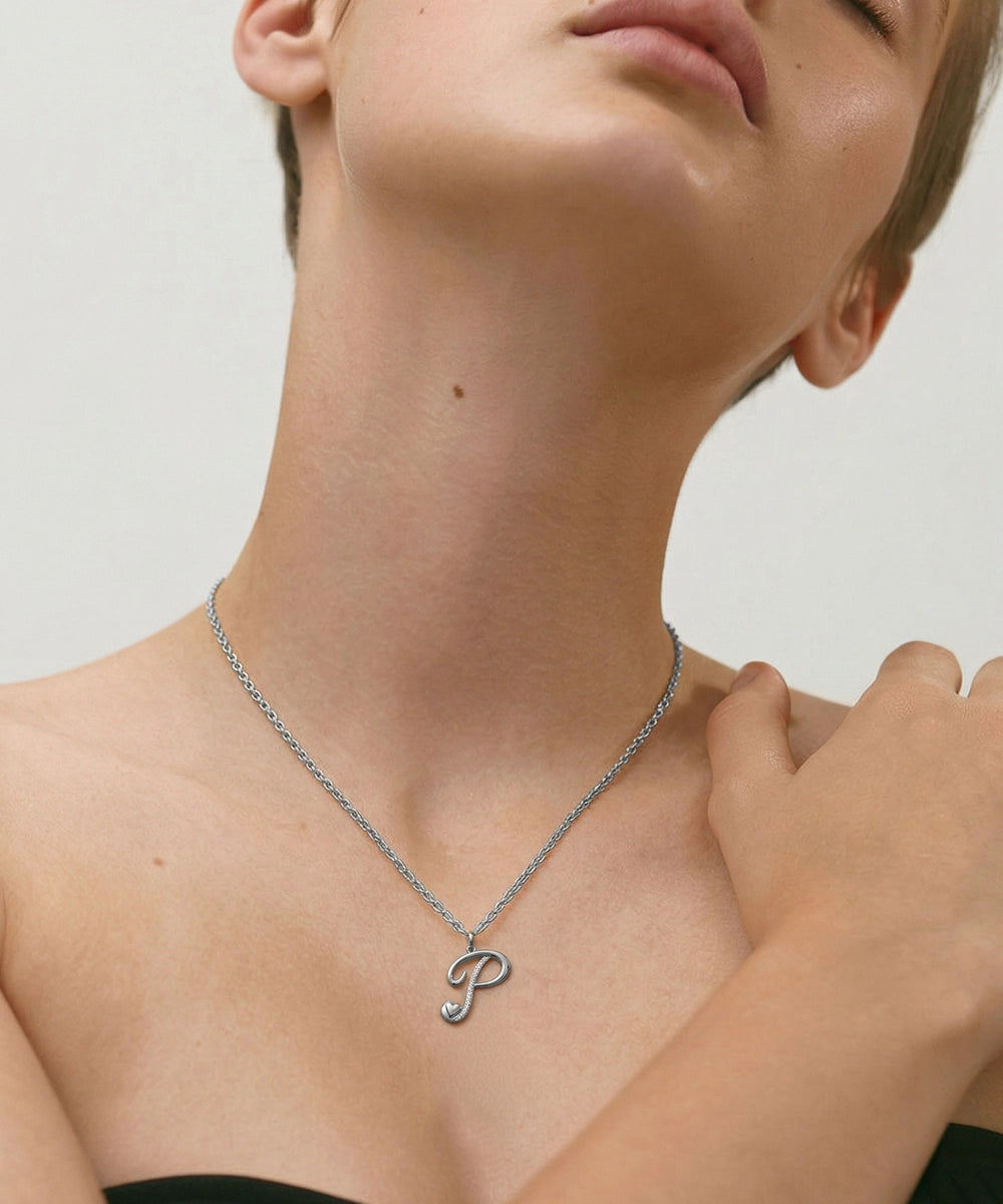 Person wearing a silver necklace with a 'P' pendant on a neutral background