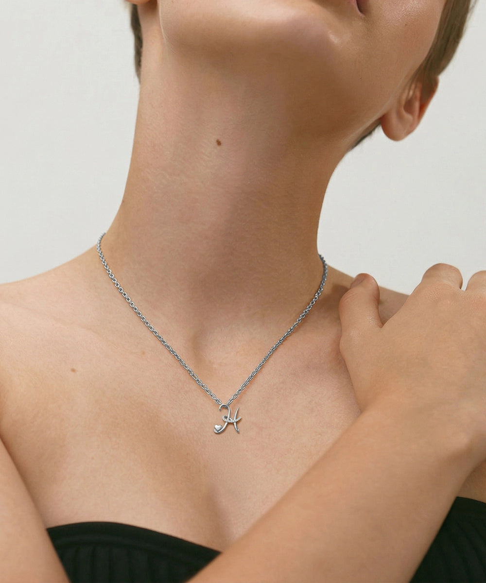 Gold necklace with a cat-shaped pendant worn by a person on a plain background