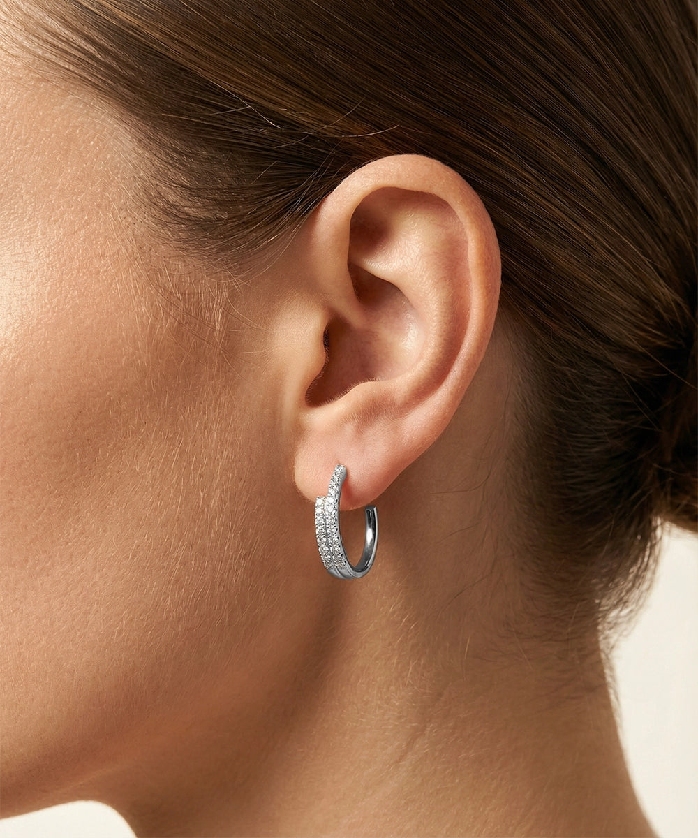 Close-up of an ear wearing a silver hoop earring with a blurred background