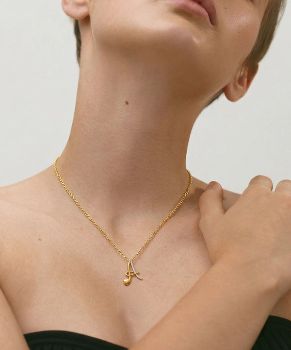 Gold necklace with a pendant on a person against a neutral background