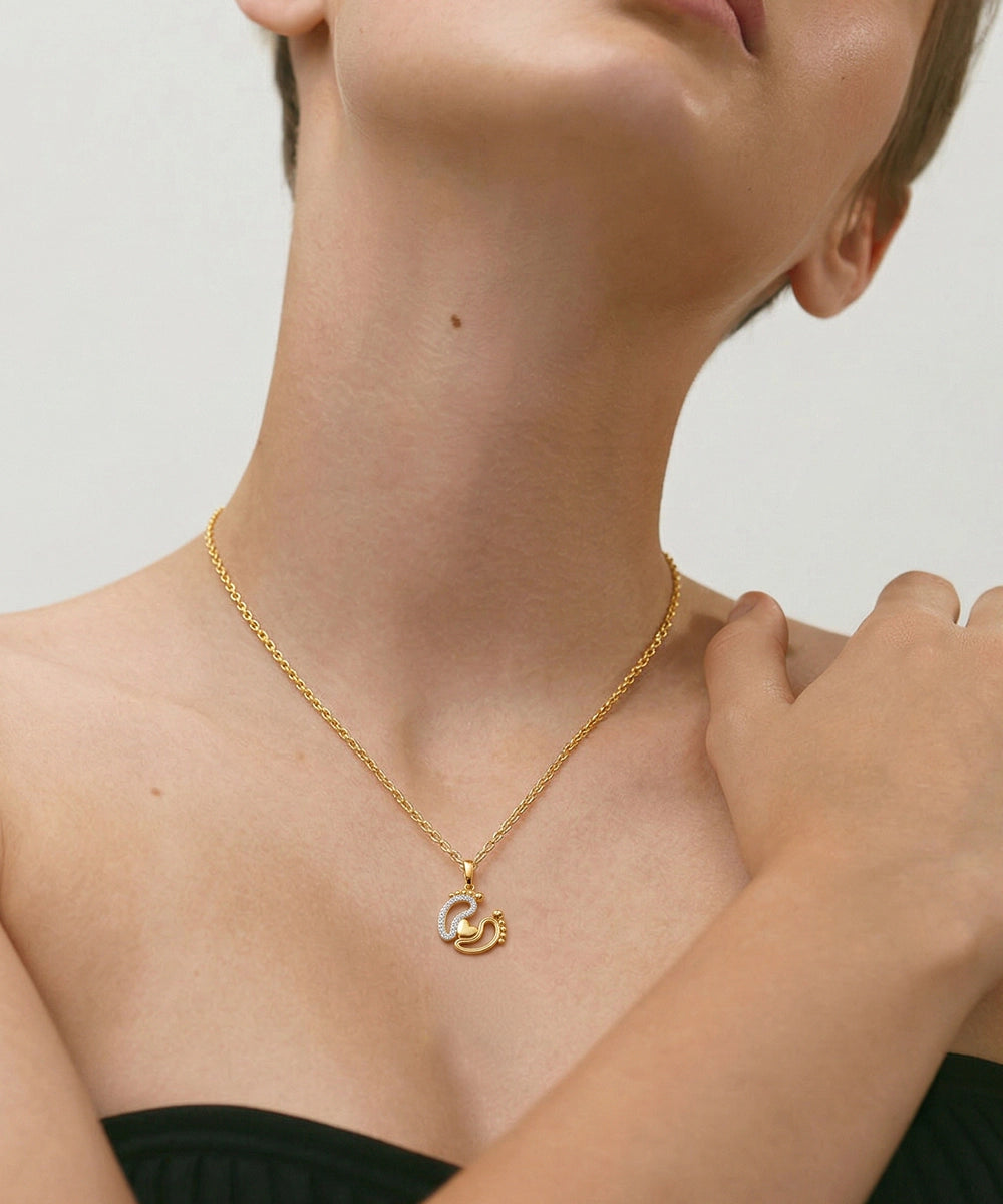 Gold necklace with a pendant worn by a person on a neutral background