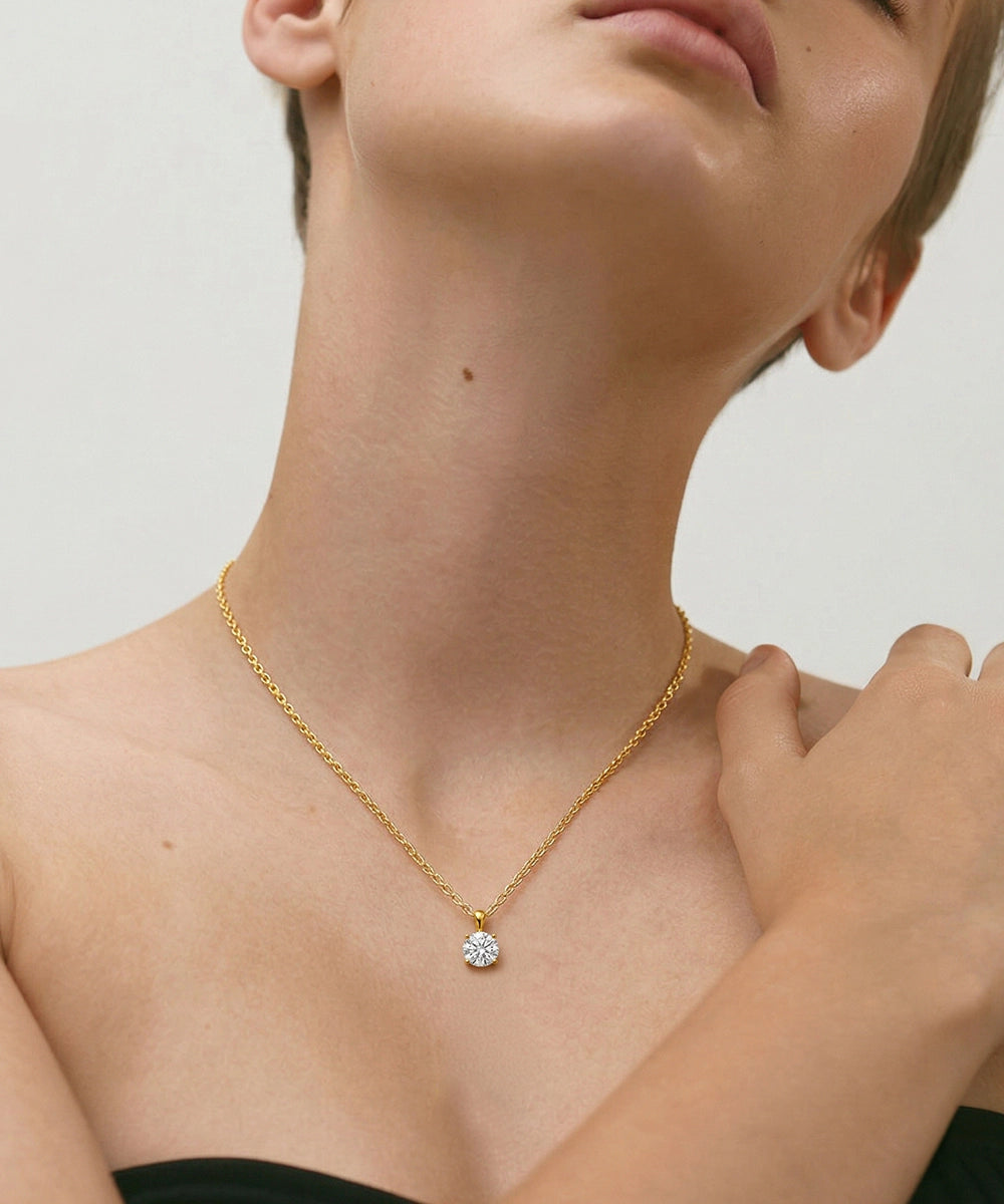 Gold necklace with a diamond pendant on a neutral background