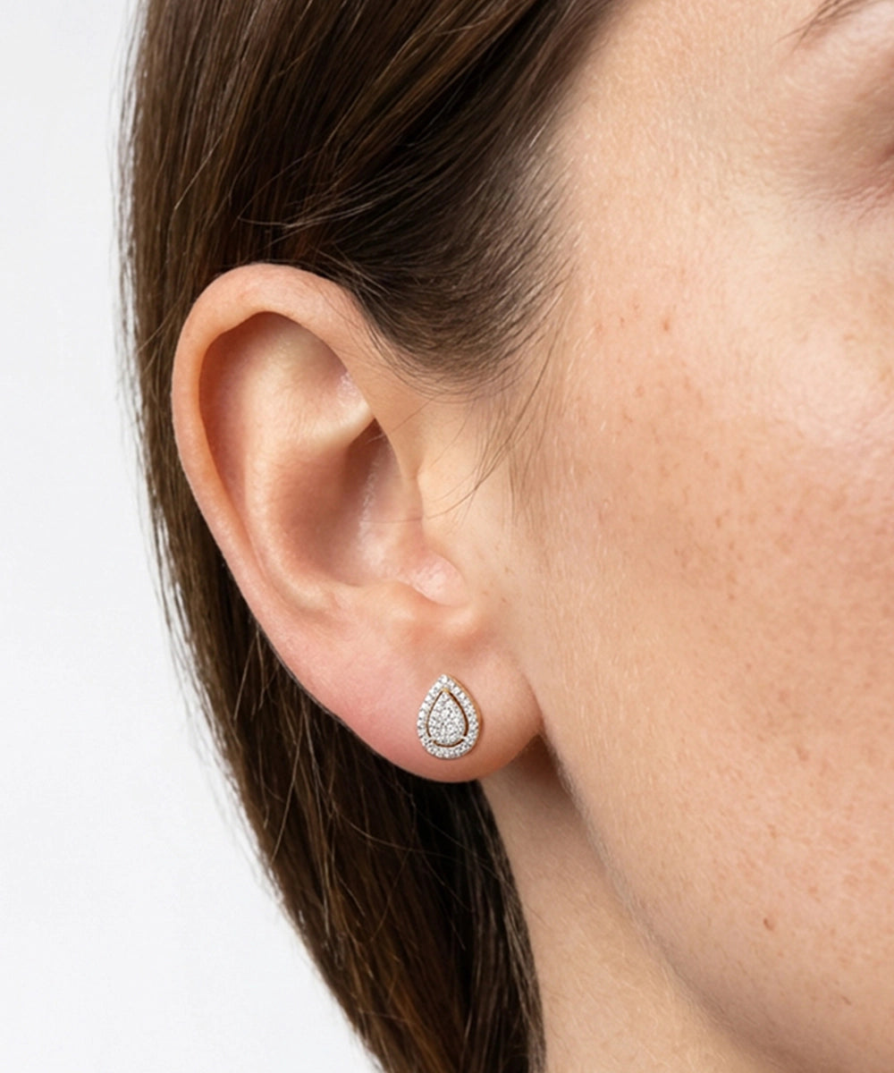 Close-up of an ear wearing a teardrop-shaped earring on a white background