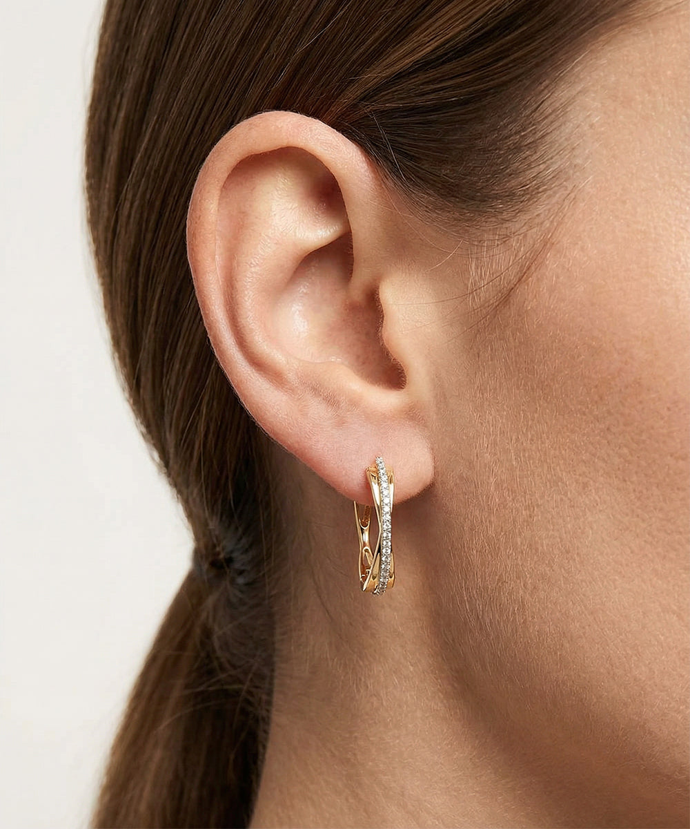 Close-up of a person wearing a gold hoop earring on a neutral background
