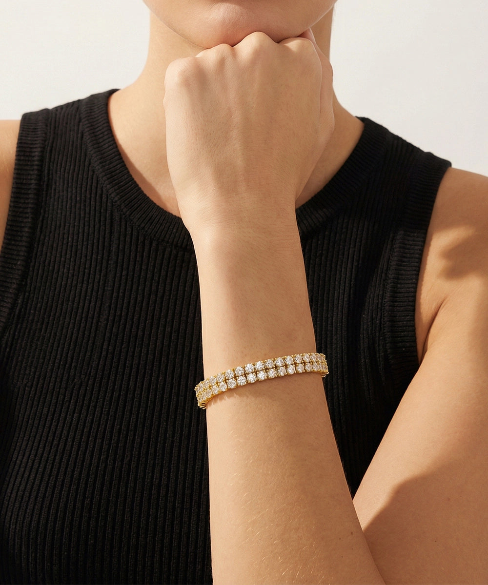 Person wearing a gold bracelet on a plain background