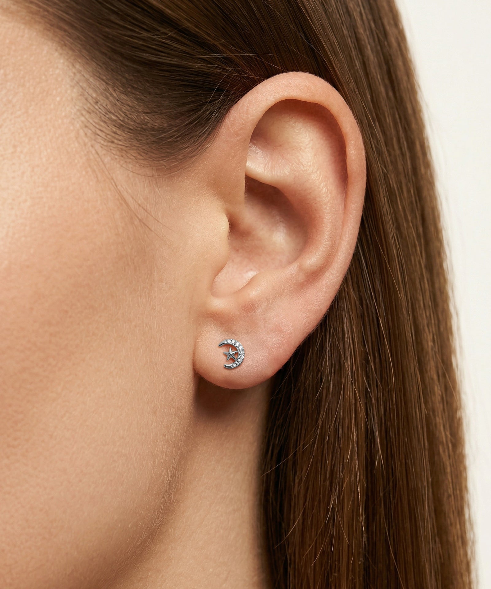 Close-up of an ear wearing a small earring with a white background