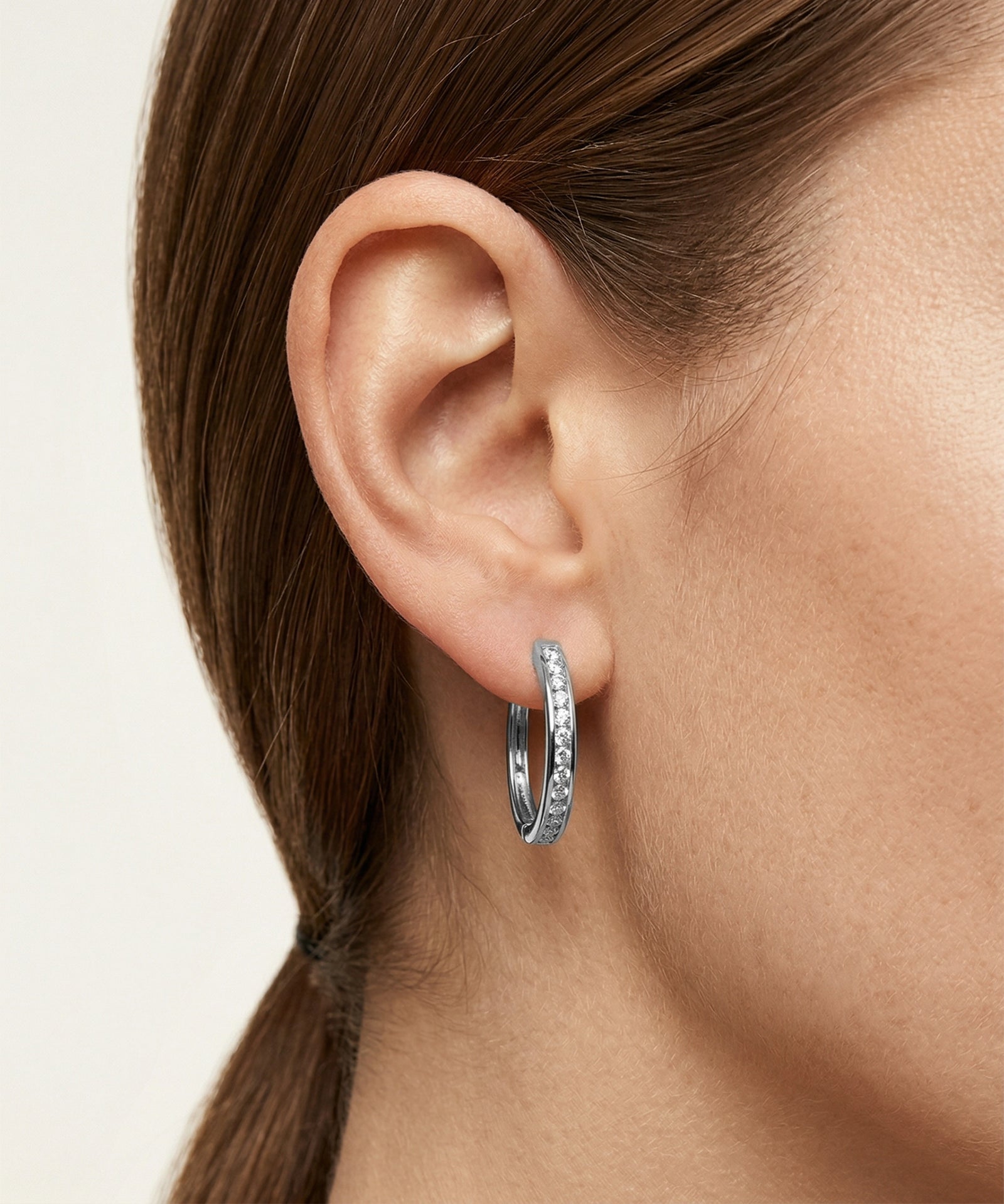 Gold hoop earrings worn by a person with a neutral background