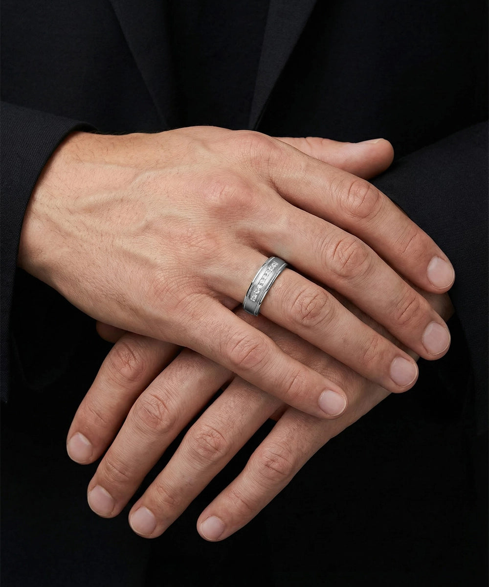 Close-up of a hand wearing a silver ring with a black background