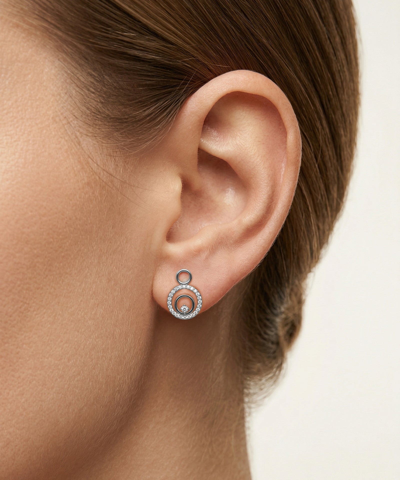 Close-up of an ear wearing a silver earring with a white background