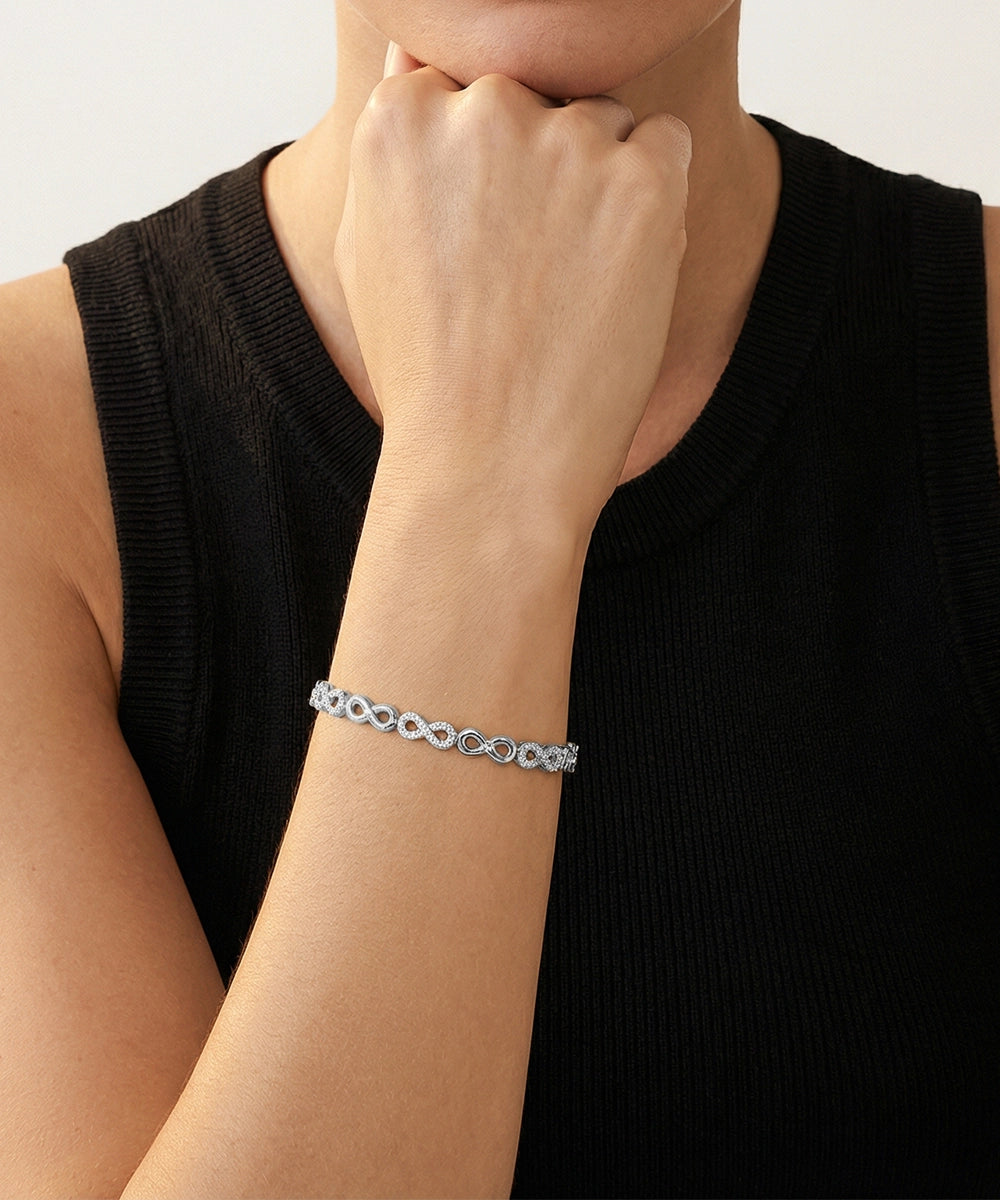 Person wearing a silver bracelet on a plain background