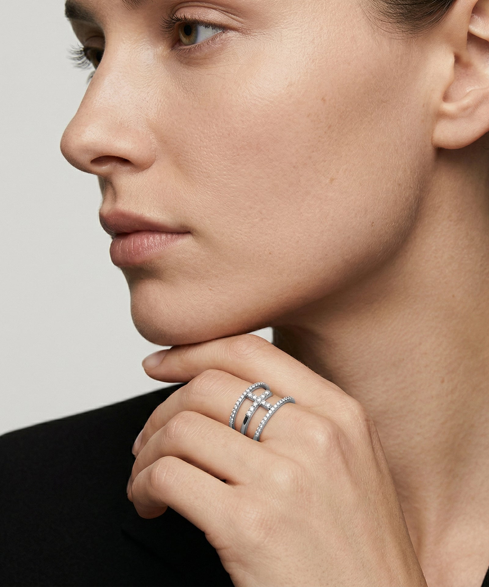 Close-up of a woman's hand wearing multiple rings on a neutral background