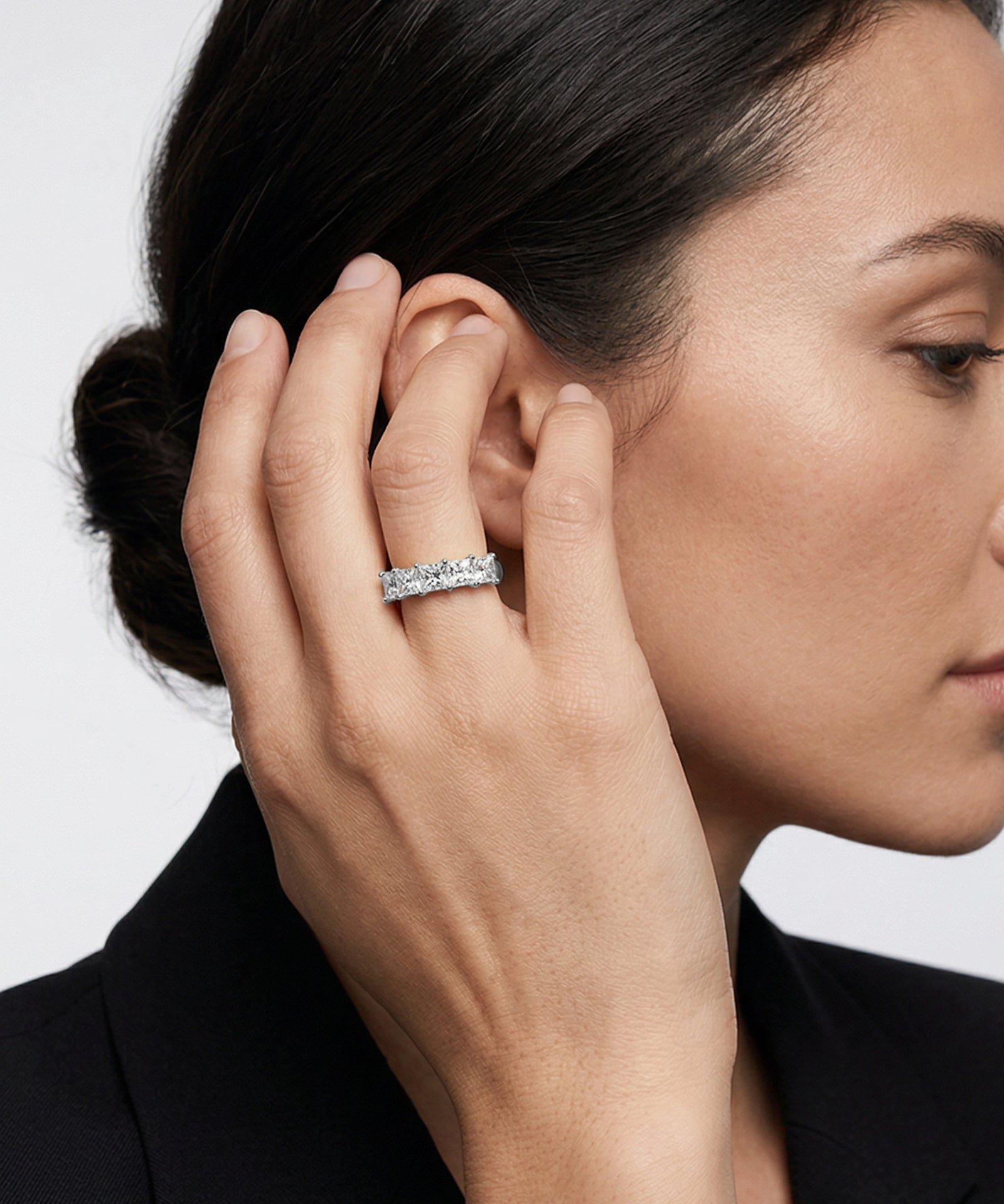 Woman wearing a diamond ring on her hand with a plain background