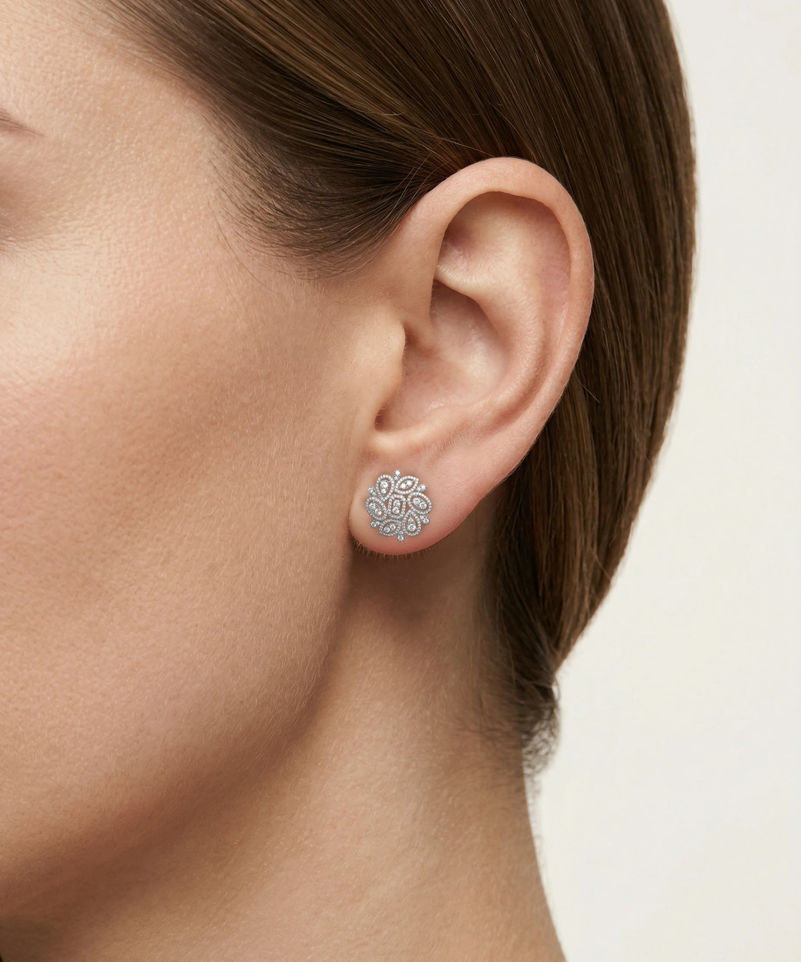 Close-up of an ear wearing a silver earring with a white background