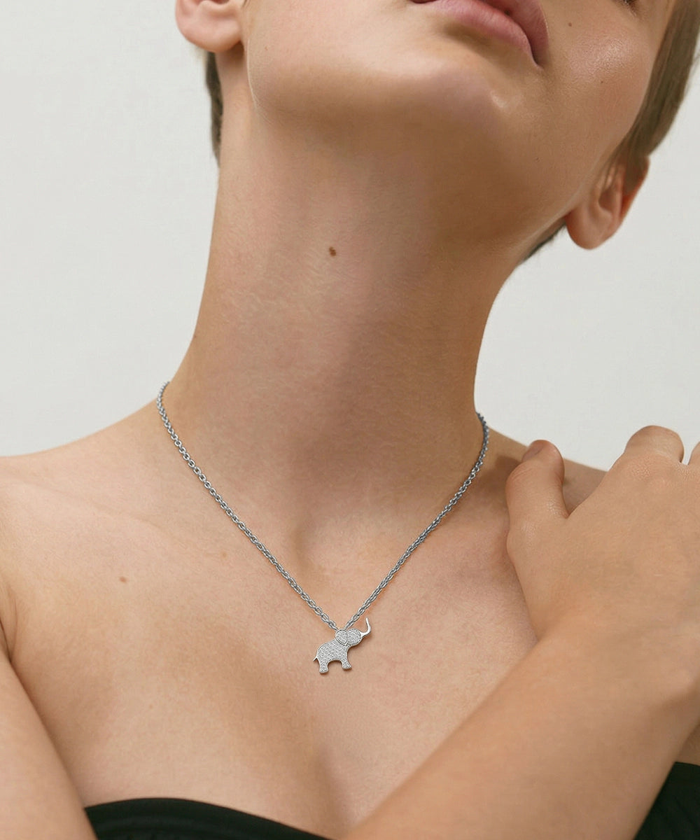 Person wearing a delicate necklace with a small pendant on a plain background