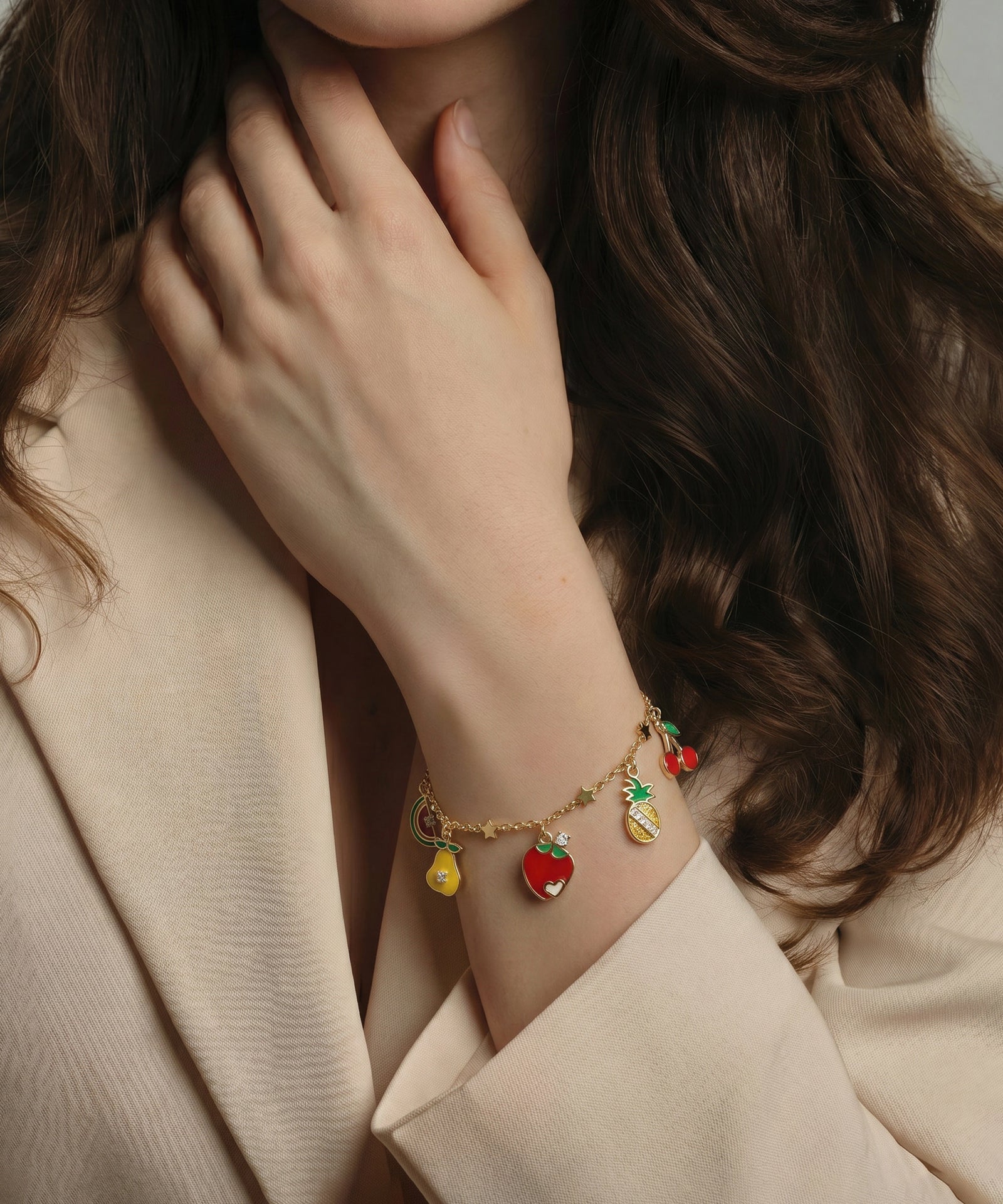 Close-up of a person wearing a bracelet with colorful charms, with a neutral background.