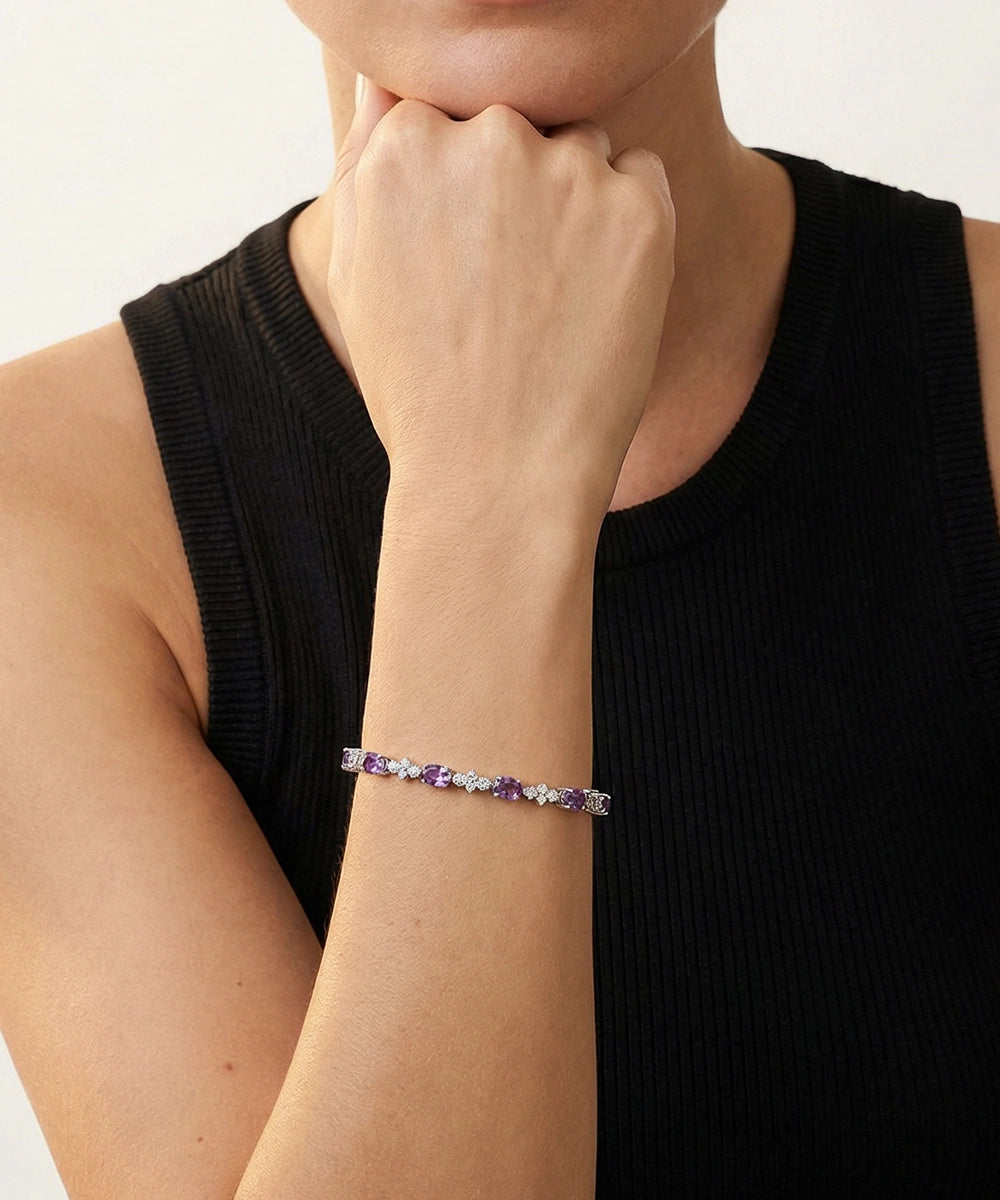 Person wearing a bracelet with purple stones on a plain background