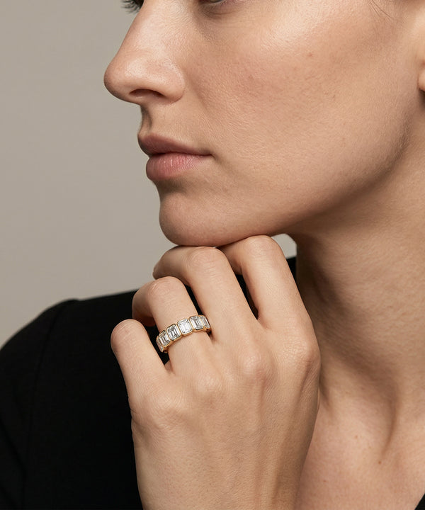 Close-up of a woman's hand wearing a diamond ring on a neutral background