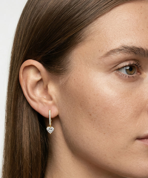 Close-up of a woman wearing a heart-shaped diamond earring.
