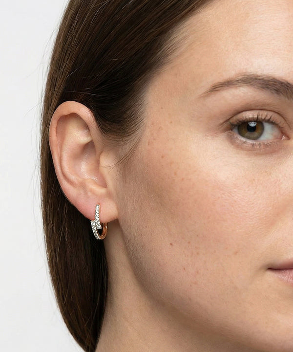 Close-up of a woman wearing a diamond earring on a white background