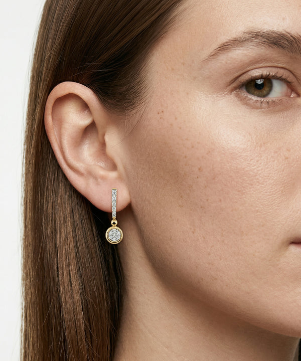 Close-up of a woman wearing a silver earring with a clear gemstone.