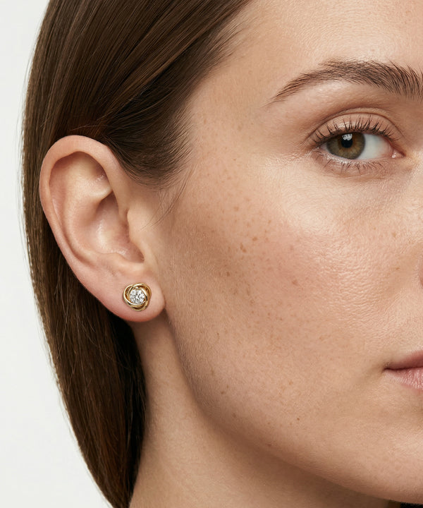 Close-up of a woman wearing gold earrings with a white background