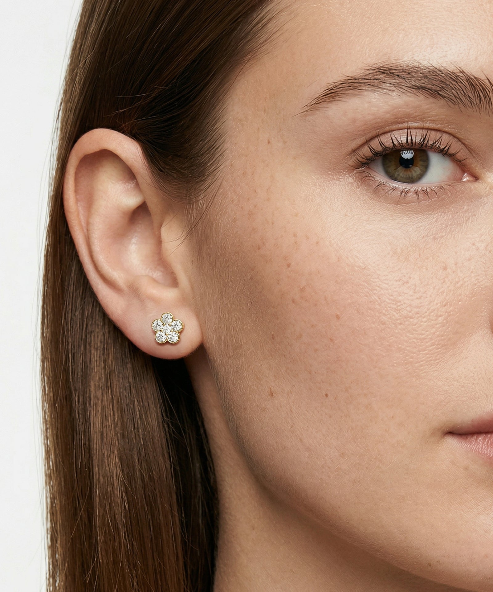 Close-up of a woman wearing a diamond earring on a plain background
