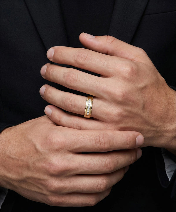Close-up of a person's hands with a gold ring on one finger, wearing a black suit.