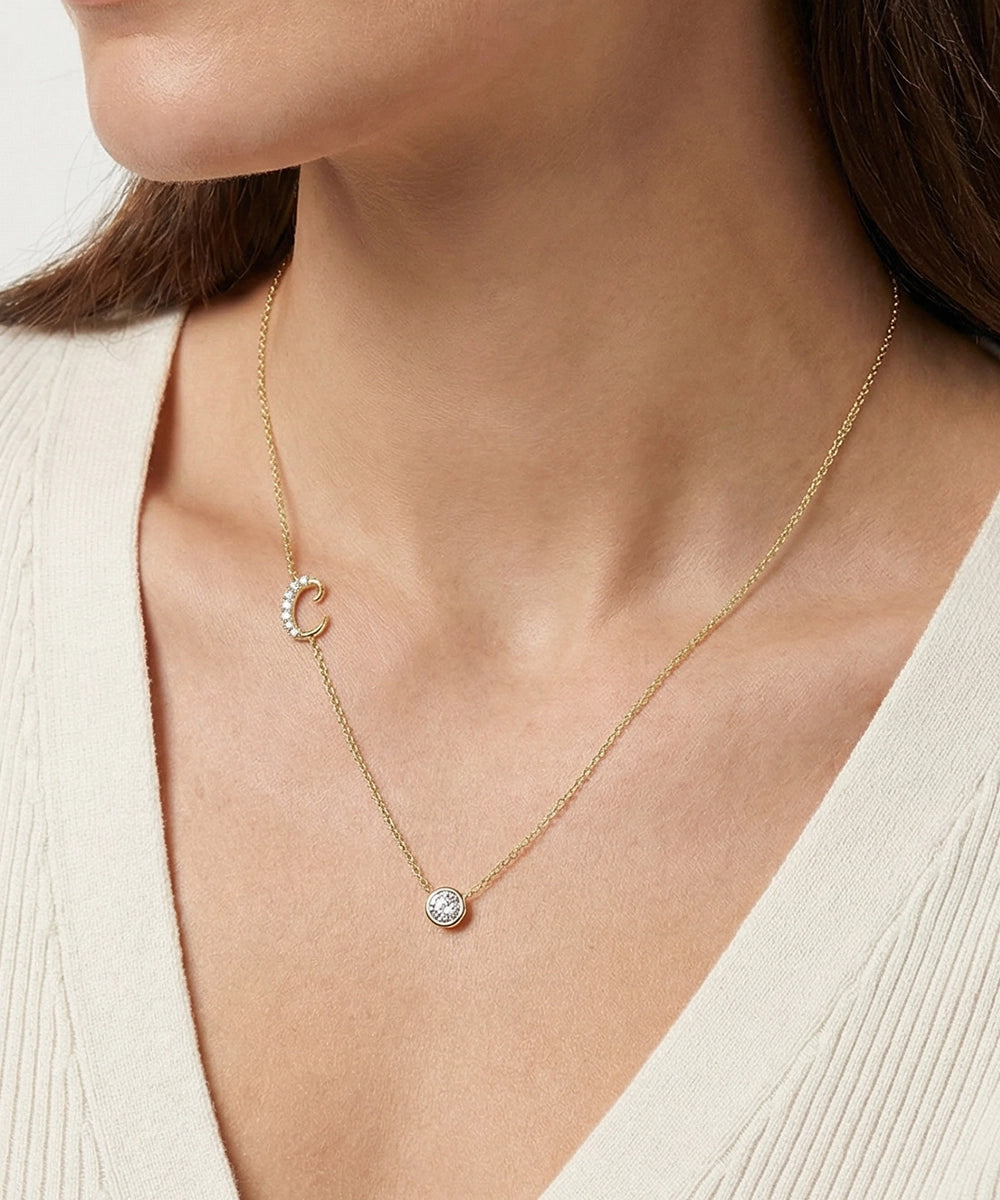 Gold necklace with a small pendant worn by a person against a neutral background
