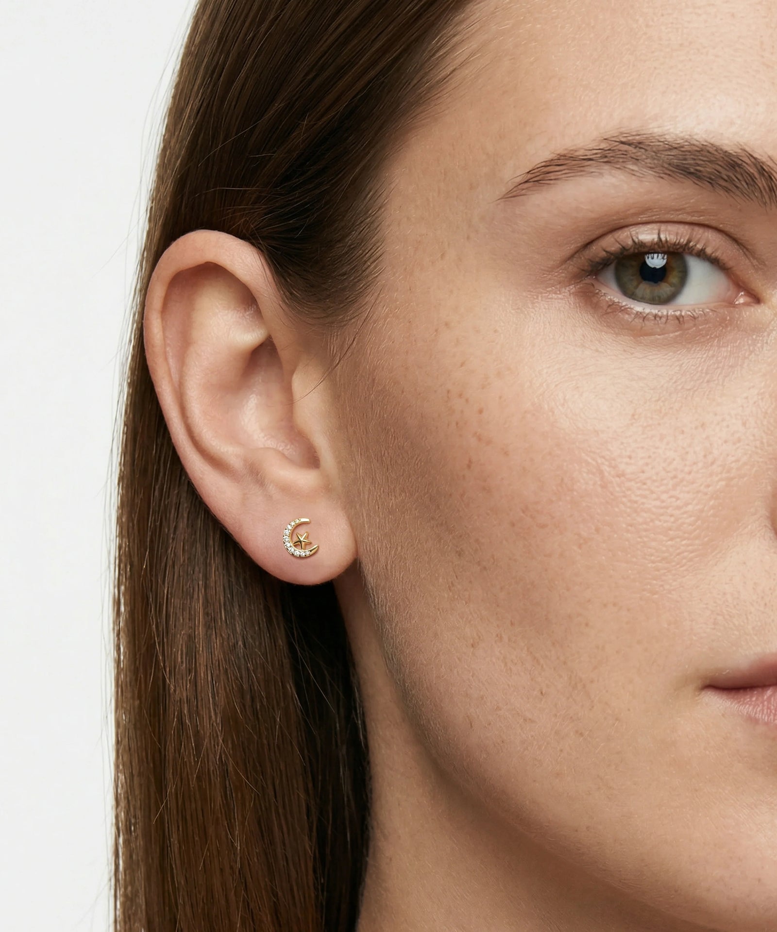 Close-up of a woman wearing a gold earring with a small round gemstone.
