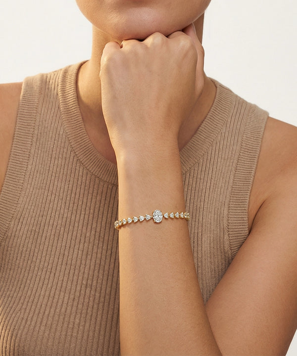 Woman wearing a gold bracelet with a beige sleeve and neutral background