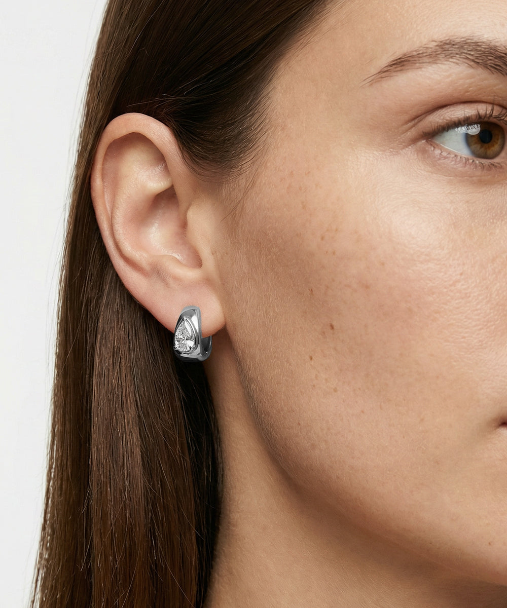 Close-up of a woman wearing a silver earring with a clear gemstone.