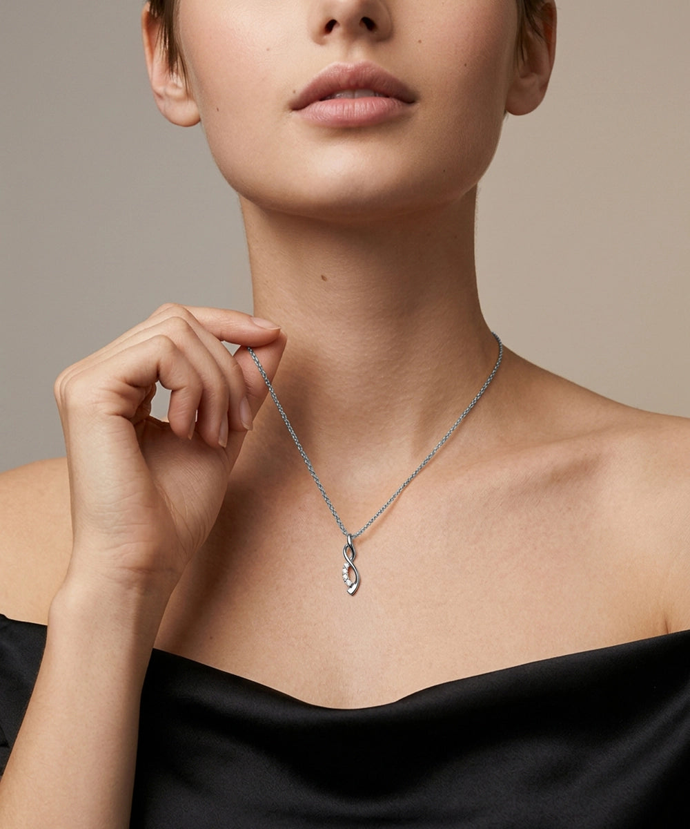 Woman wearing a silver necklace with a black top against a neutral background