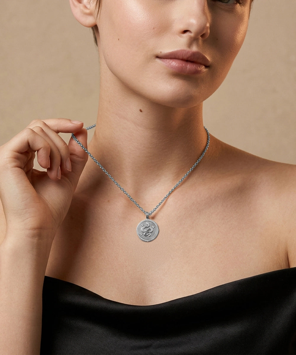 Woman wearing a silver necklace with a circular pendant against a beige background