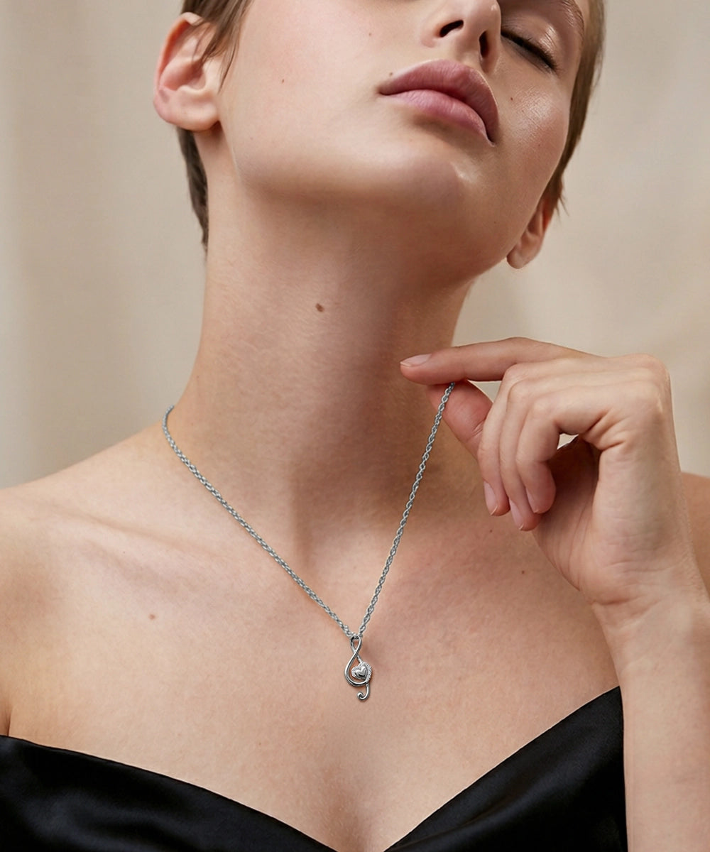 Woman wearing a gold necklace with a small pendant, touching her chin.