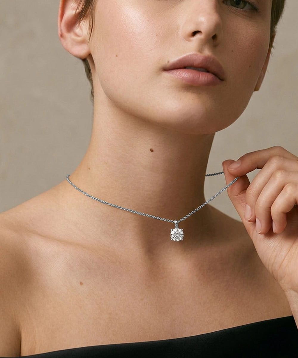 Woman wearing a silver necklace with a clear pendant against a neutral background