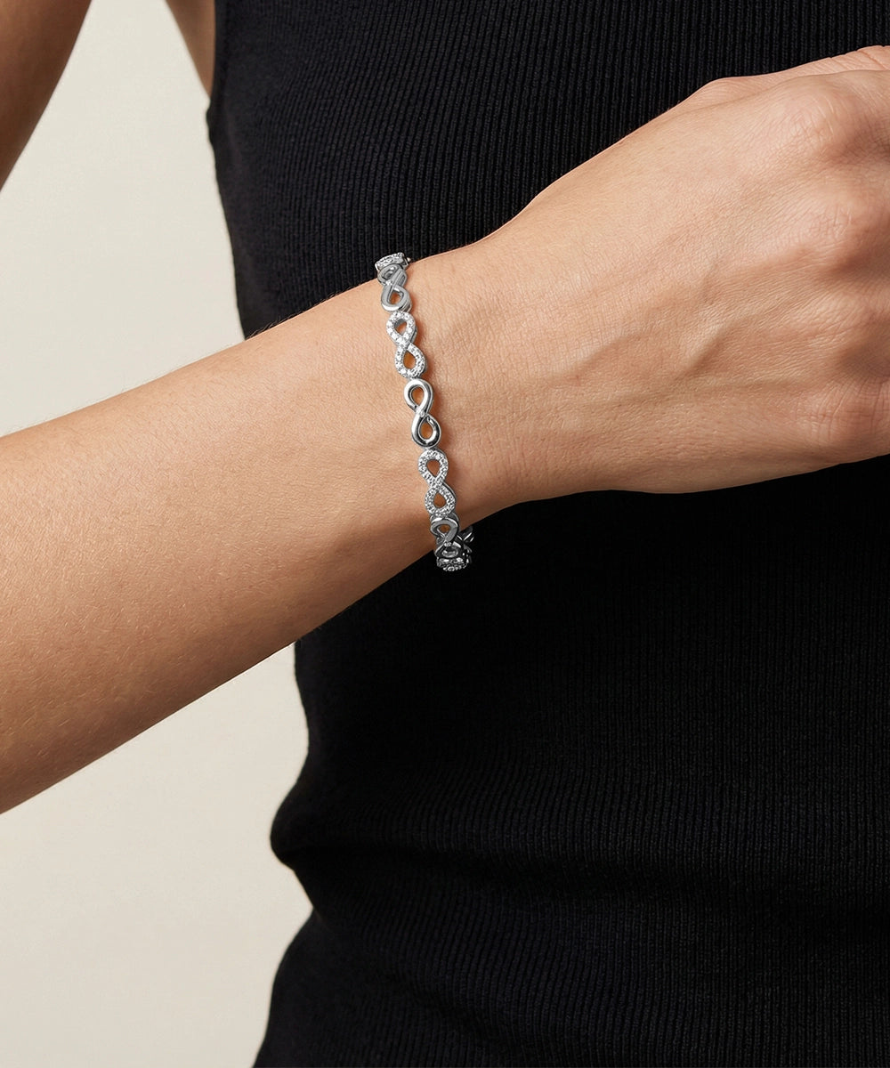Silver bracelet on a person's wrist with a plain background