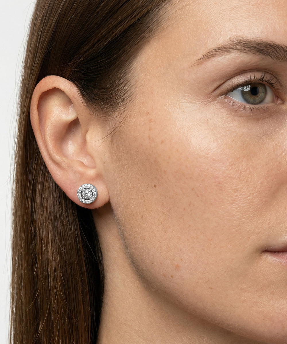 Close-up of a woman wearing a diamond earring with a plain background