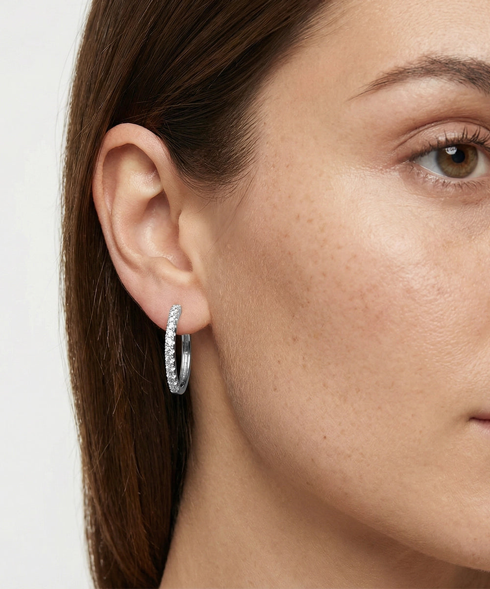 Close-up of a woman wearing a silver hoop earring against a white background