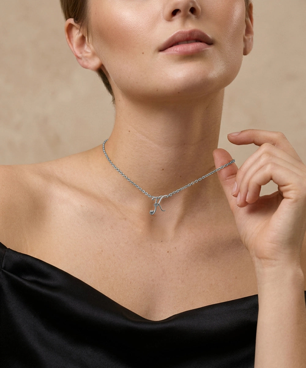Woman wearing a silver necklace with a small pendant against a beige background