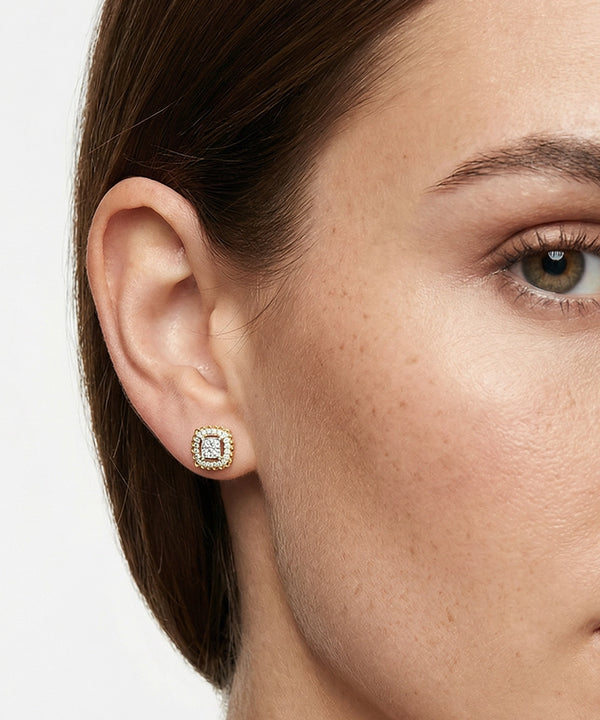 Close-up of a woman wearing gold earrings with a diamond center on a white background