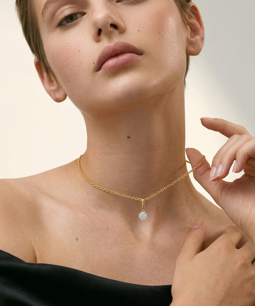 Close-up of a person wearing a gold necklace with a diamond pendant on a neutral background
