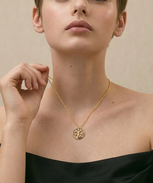 Woman wearing a gold necklace with a circular pendant against a neutral background
