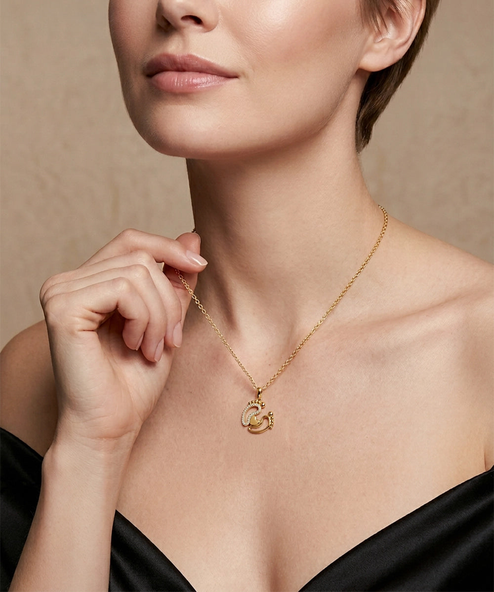 Woman wearing a gold necklace with a pendant against a neutral background