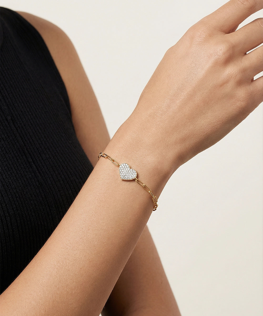 Silver bracelet with heart-shaped diamond design on a wrist against a neutral background