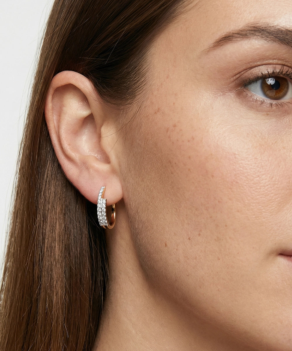 Close-up of a person wearing a gold hoop earring with a white background