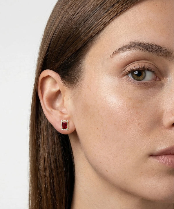 Close-up of a woman wearing a red gemstone earring with a white background