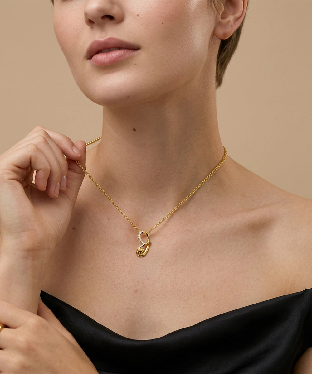 Woman wearing a gold necklace with a unique pendant against a beige background