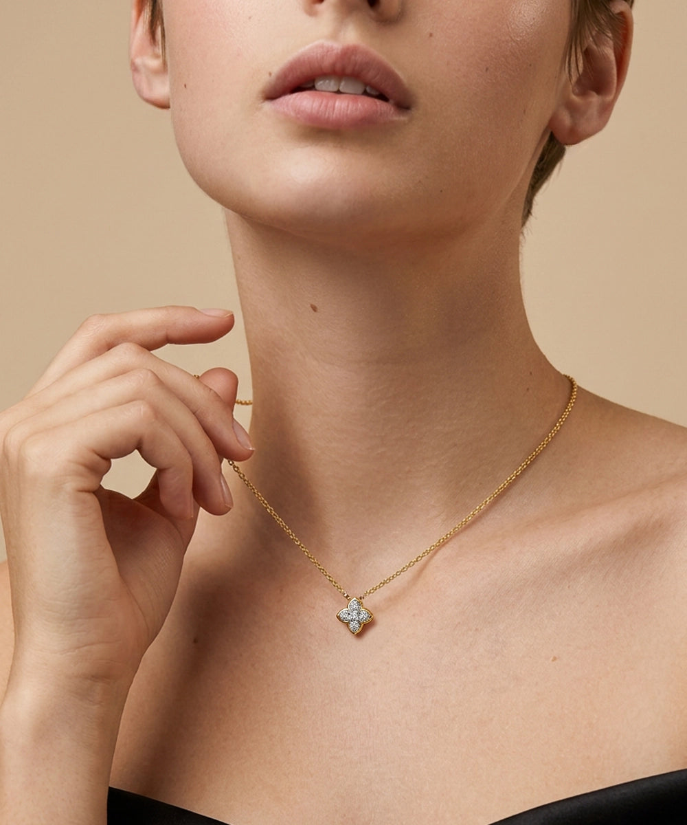Close-up of a person wearing a gold necklace with a diamond pendant on a beige background