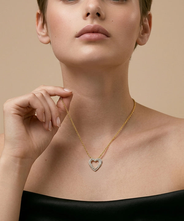 Woman wearing a silver necklace with a heart pendant against a beige background