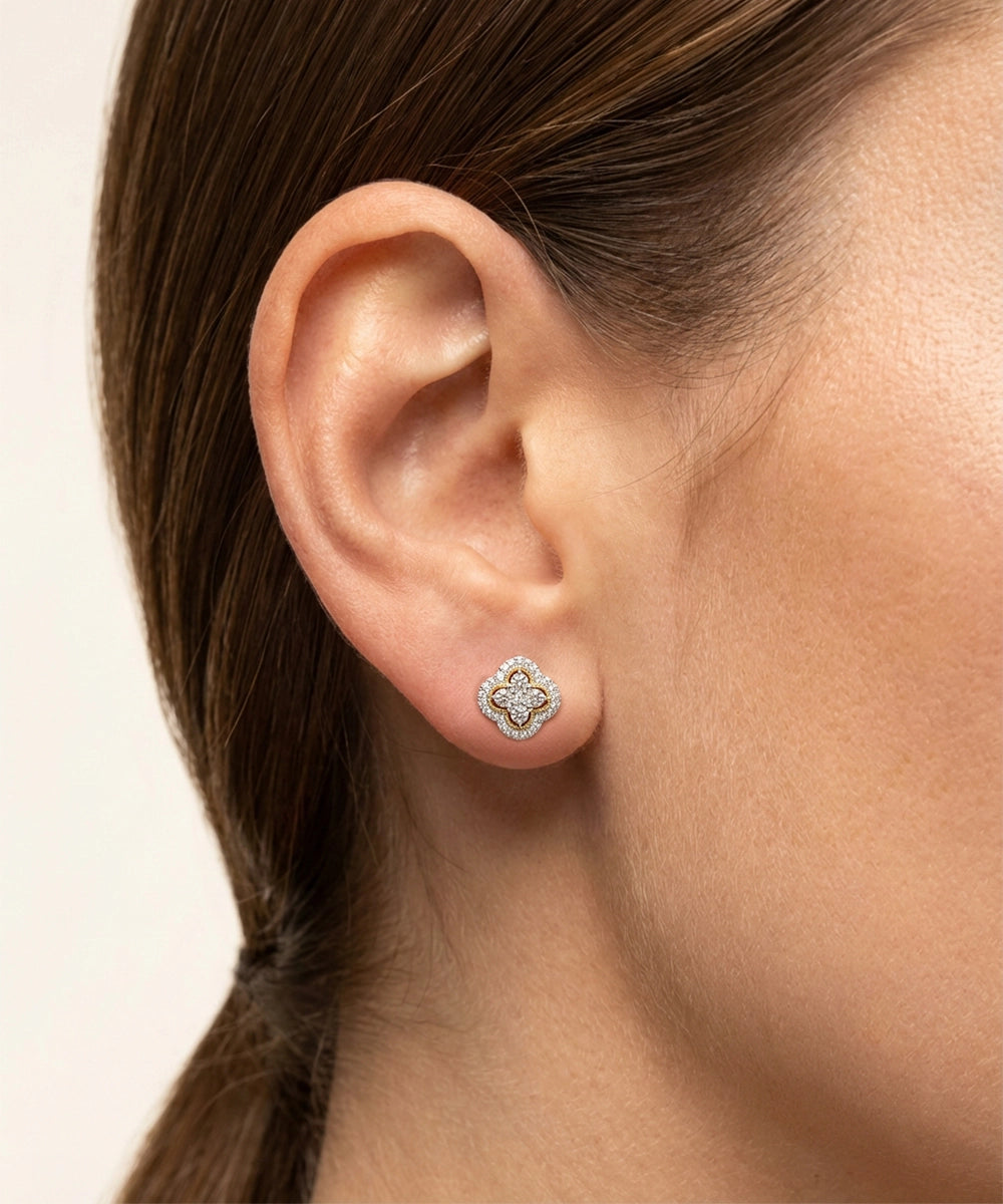 Close-up of an ear wearing a diamond stud earring with a plain background